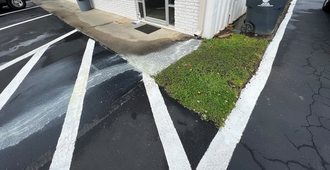 Roof wash water discharging into parking lot. 