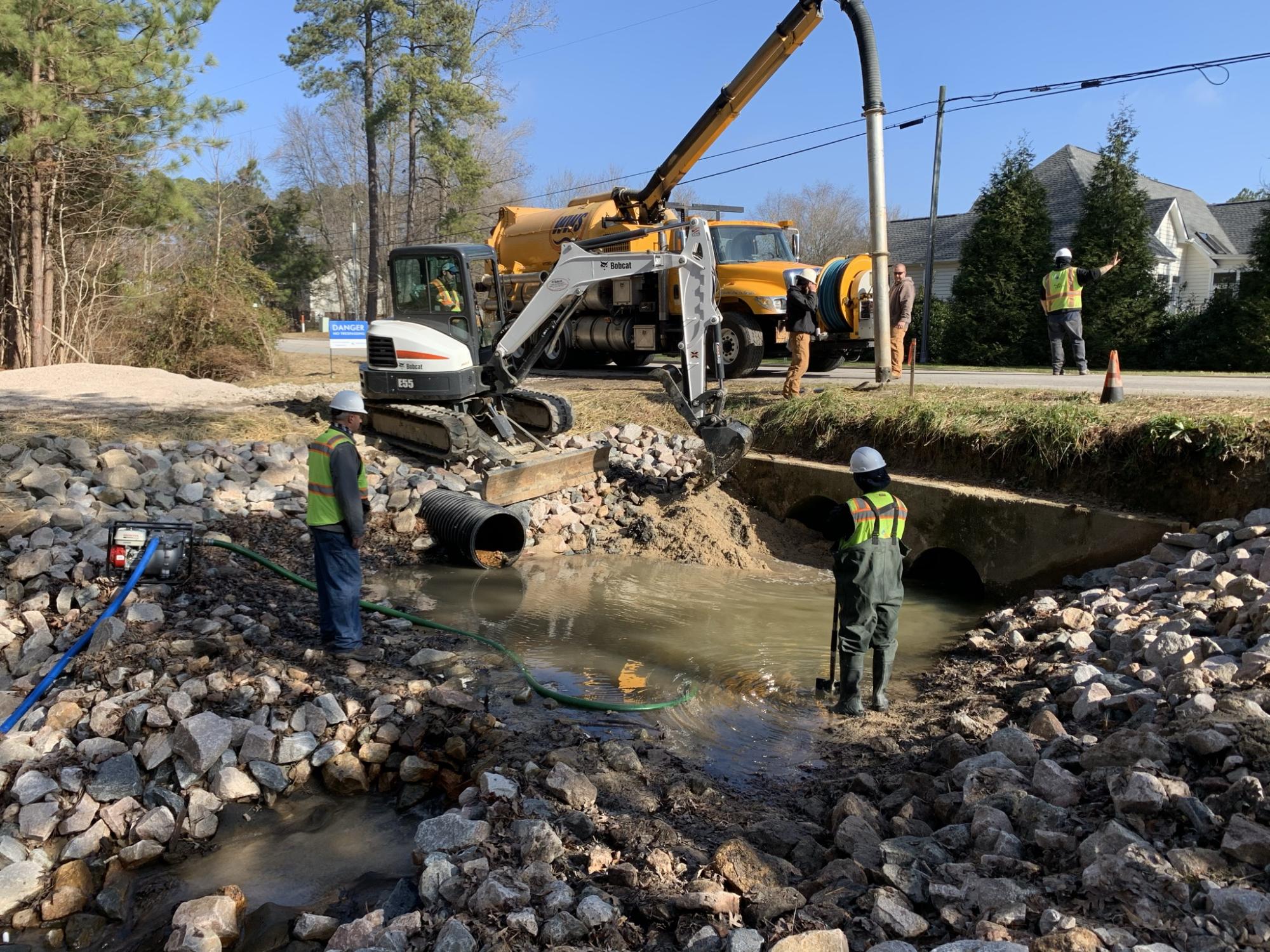 Public Works staff cleaning out roadside culvert 