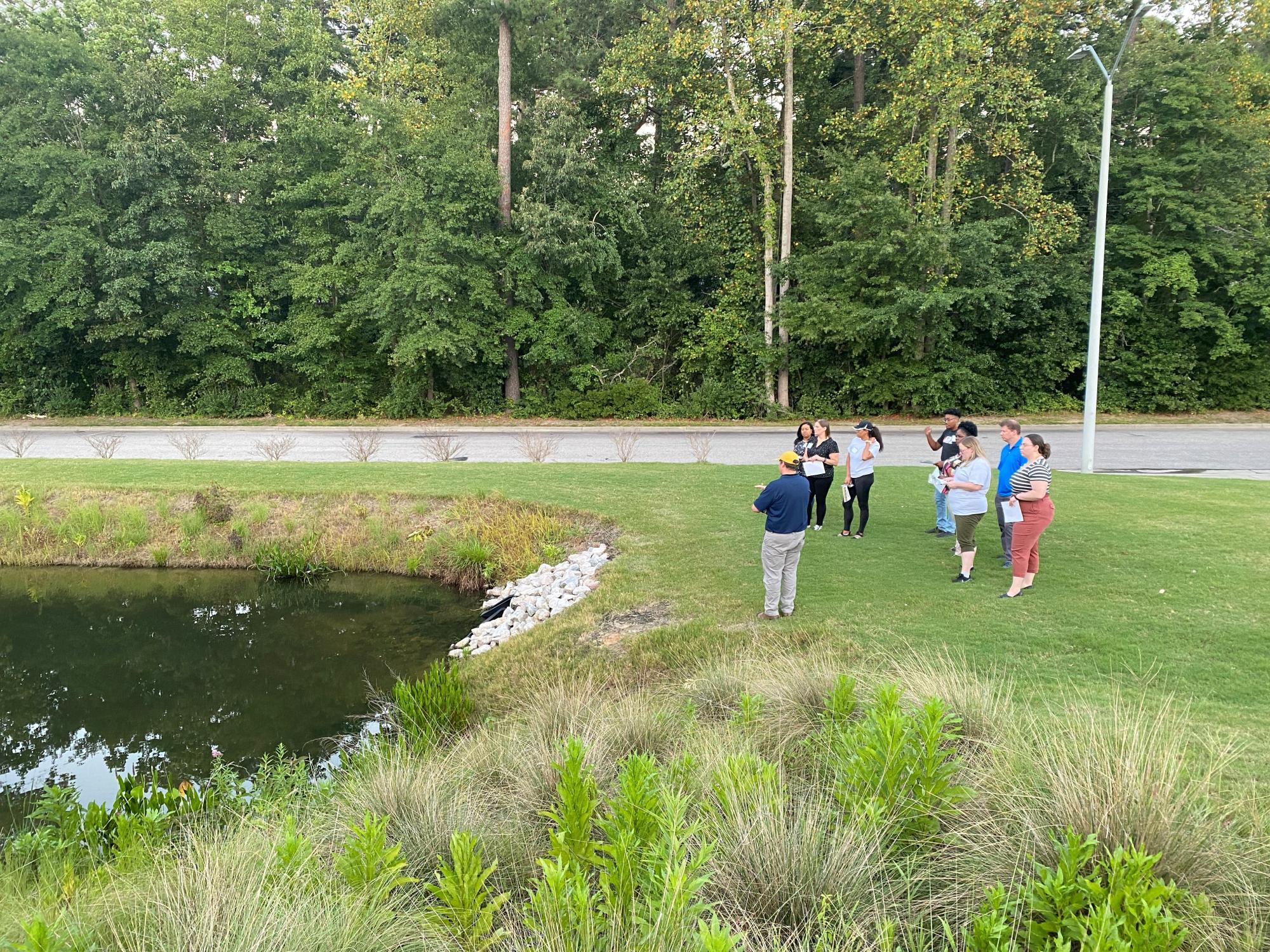 Stormwater Manager discussing stormwater pond with mayor's academy participants. 